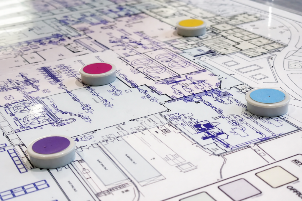 Detailed architectural site plan with colored markers placed on different sections of the blueprint layout.