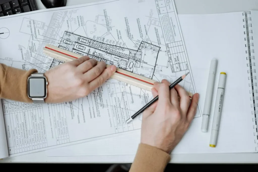 Architect reviewing architectural floor plans with ruler and pencil on construction blueprint