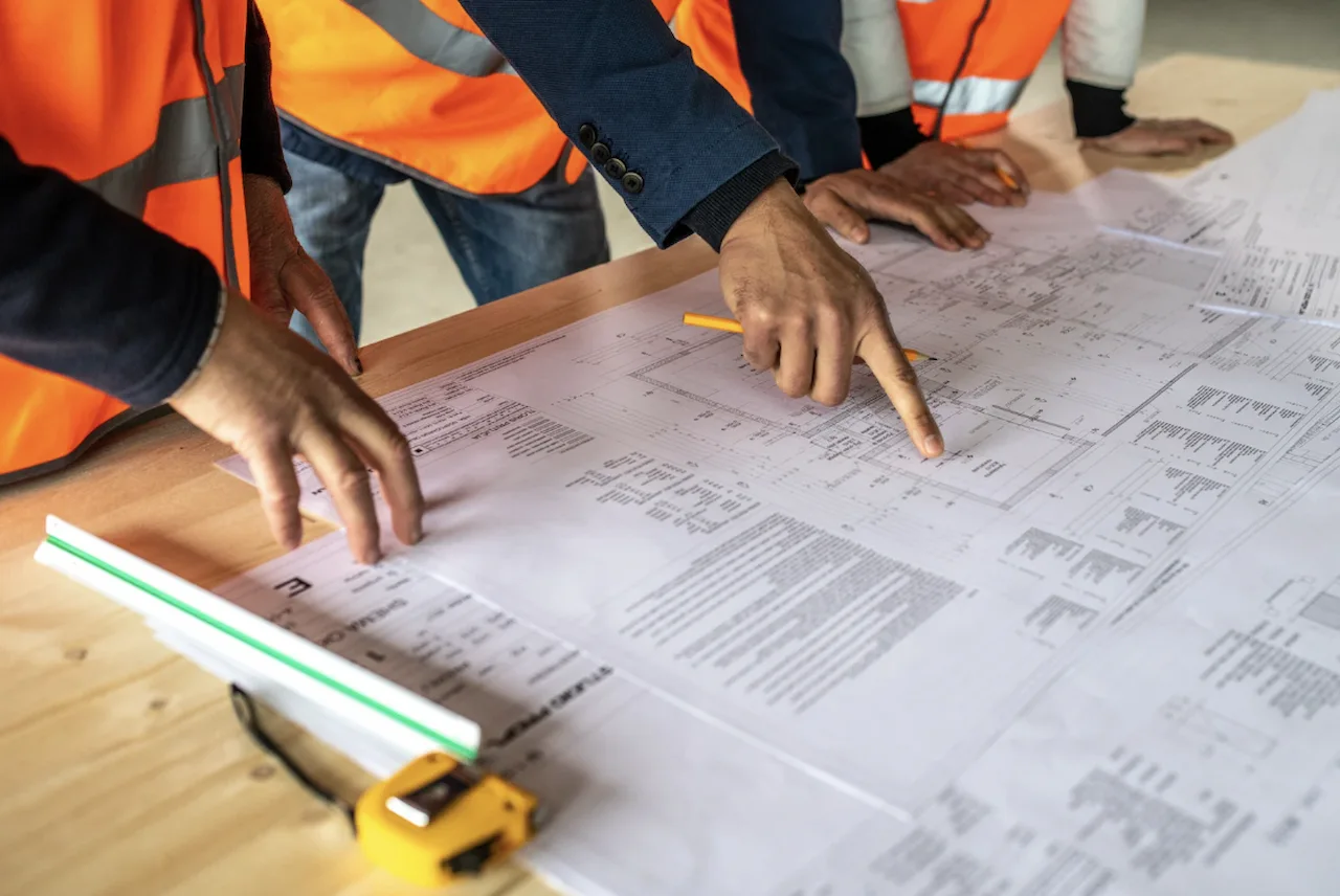 Architects reviewing residential construction blueprints and site plans during the permit planning process.