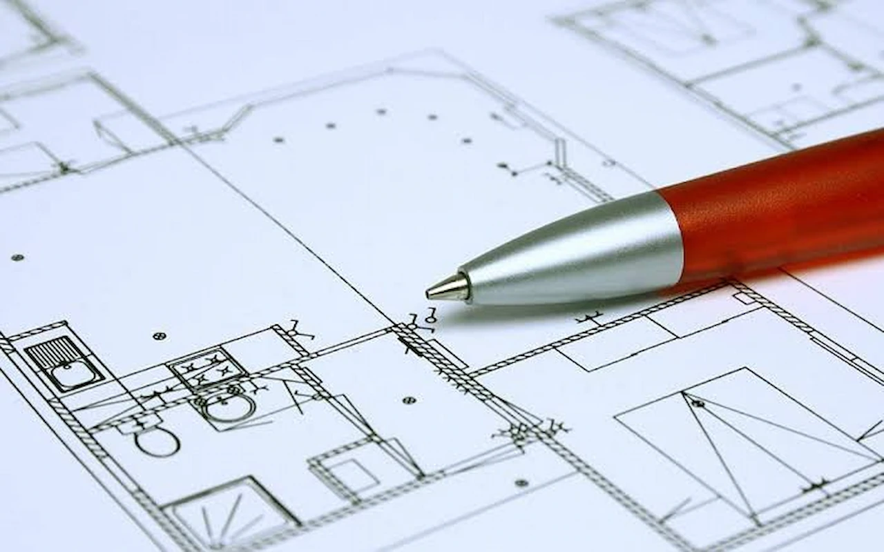 Close-up of architectural blueprint plans with a red pen highlighting residential building layout details for site planning and permit preparation.